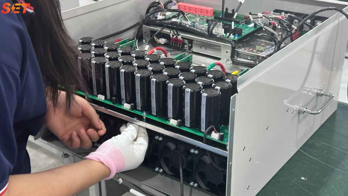 Technician assembling an active harmonic filter power module for TDD and THDi mitigation